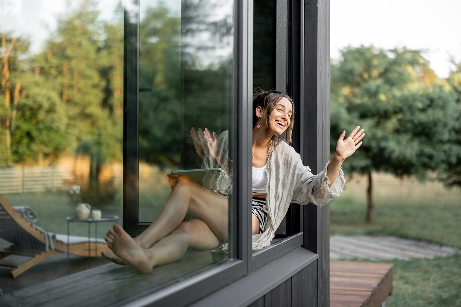 Junge Frau sitzt glücklich an Iherer neuwertigen Fensterfront